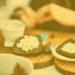 Hands of a person eating black bread with skyr on top