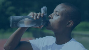 black athlete drinking more water from a bottle during training on the running track