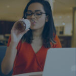 young woman drinking when bored sitting with a computer in a café