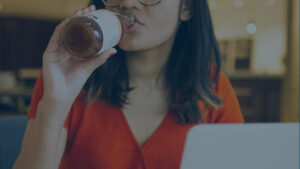 young woman drinking when bored sitting with a computer in a café