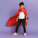 Child in superhero custome with purple background