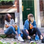 Happy teens eating and sitting on the sidewalk