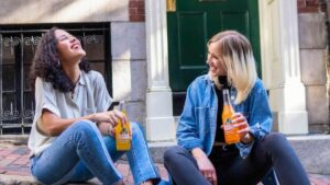 Happy teens eating and sitting on the sidewalk